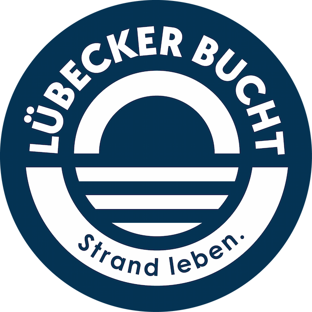Rundes Logo in Dunkelblau und Weiß mit stilisiertem Strand- und Wellenmotiv; Text: „LÜBECKER BUCHT“ und „Strand leben.“